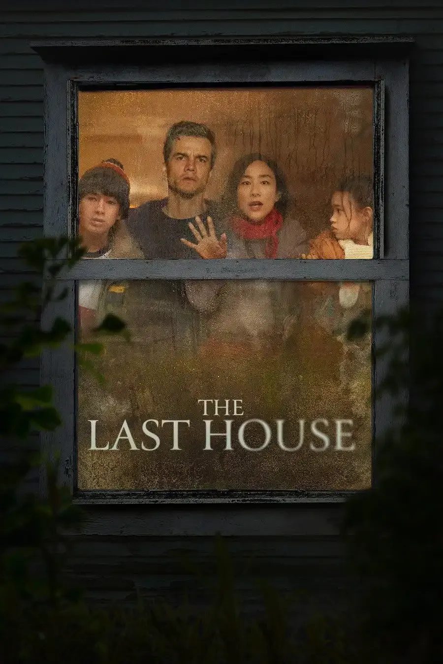 Wagner Moura and Greta Lee in a dimly lit midcentury living room with their two children, rain hammering the windows outside