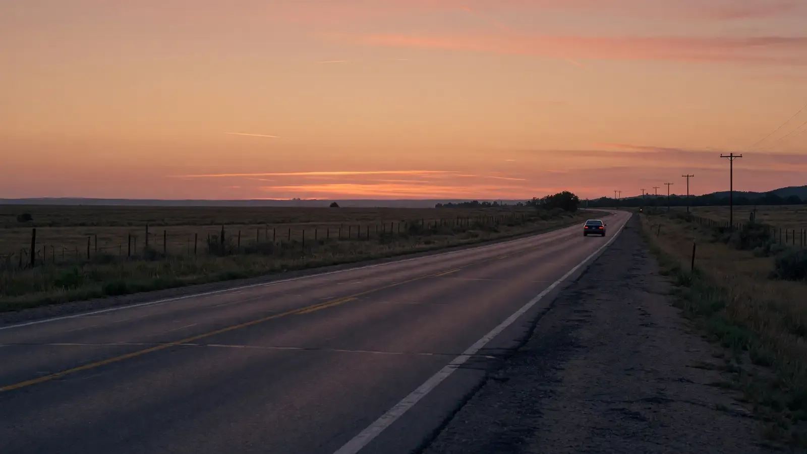 Empty two-lane highway at dusk with a single passenger-car silhouette and no readable plates, warm sky, no logos or titles.